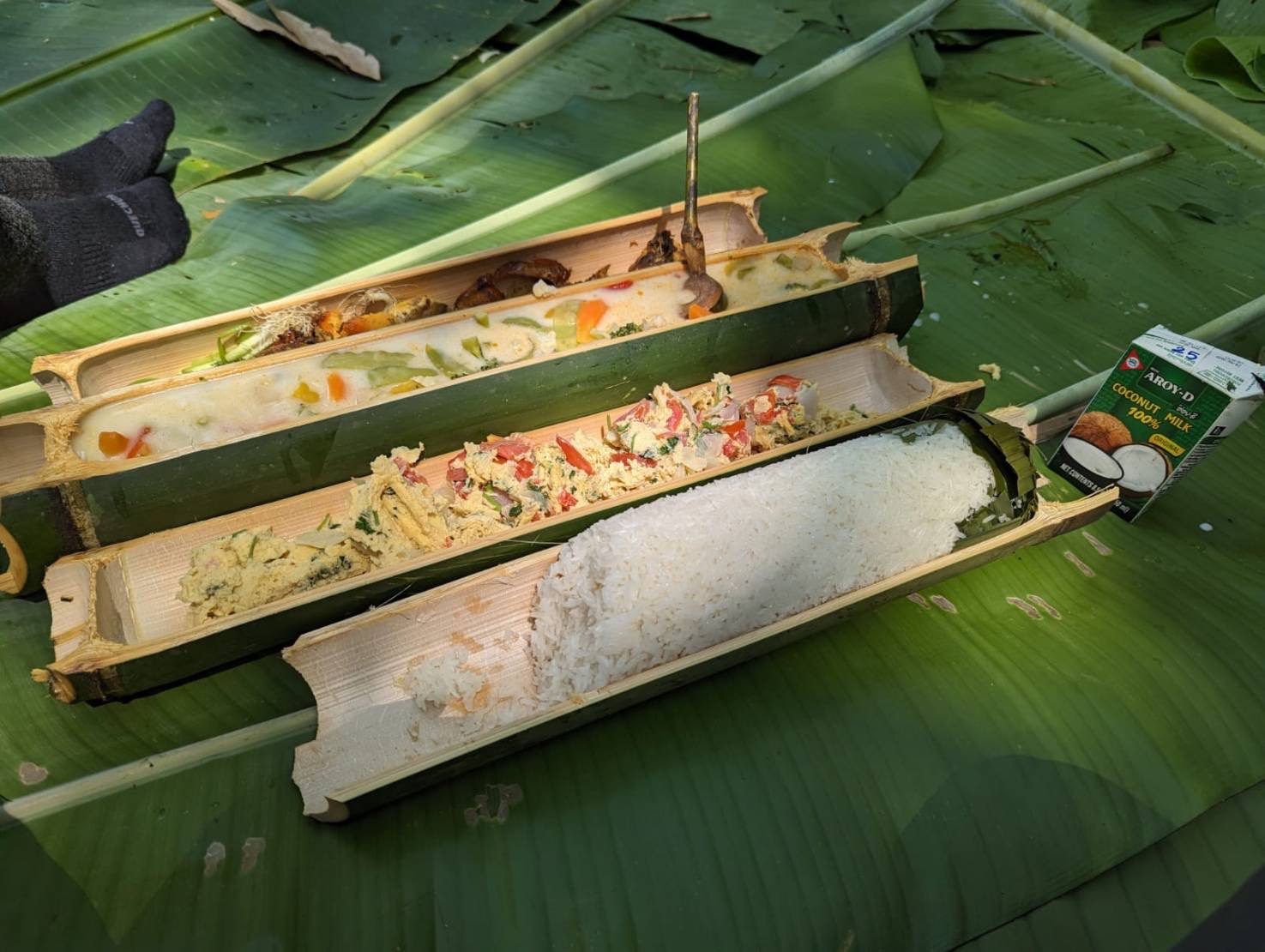 Sticky rice and curry cooked in bamboo, served on banana leaves